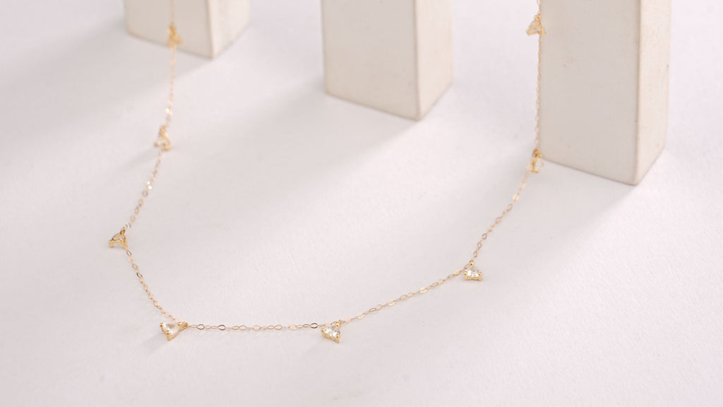 Gold necklace on a white marble stand with a white background