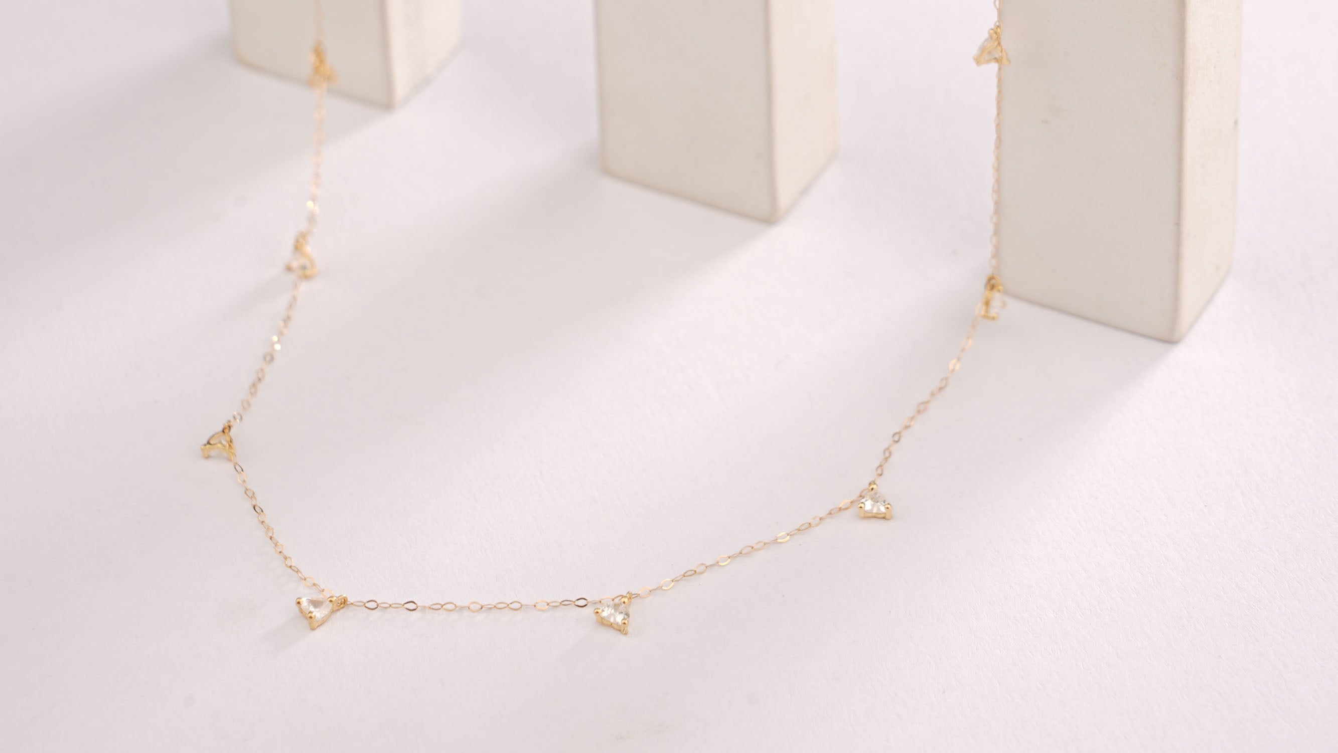 Gold necklace on a white marble stand with a white background