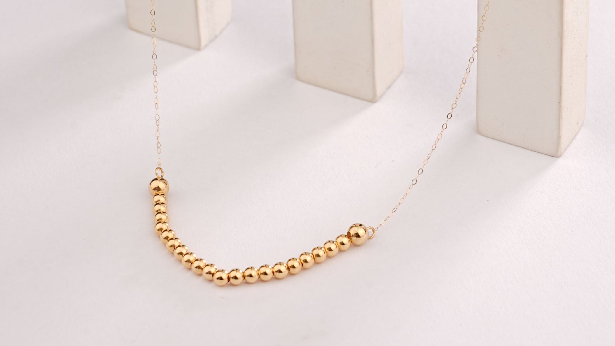 Gold chain on a white background with a white jewelry display block.
