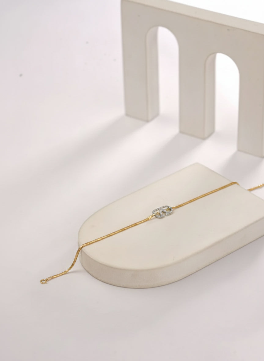 Gold bracelet on a white surface with a minimal background