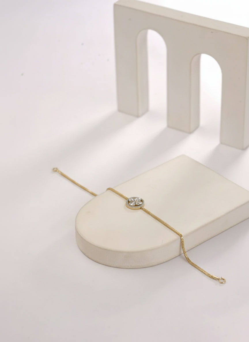 Gold bracelet with a diamond on a white stand against a light background