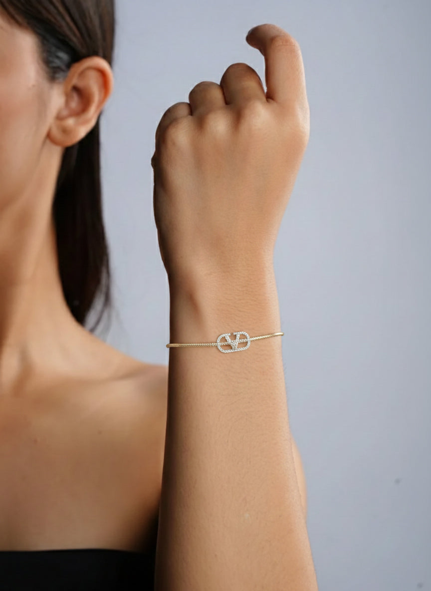 Woman wearing a delicate gold bracelet on a plain background