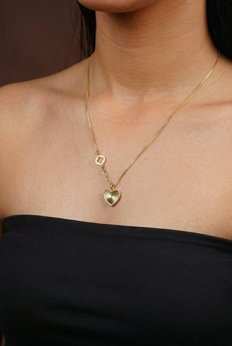 Gold necklace with a heart pendant worn by a person