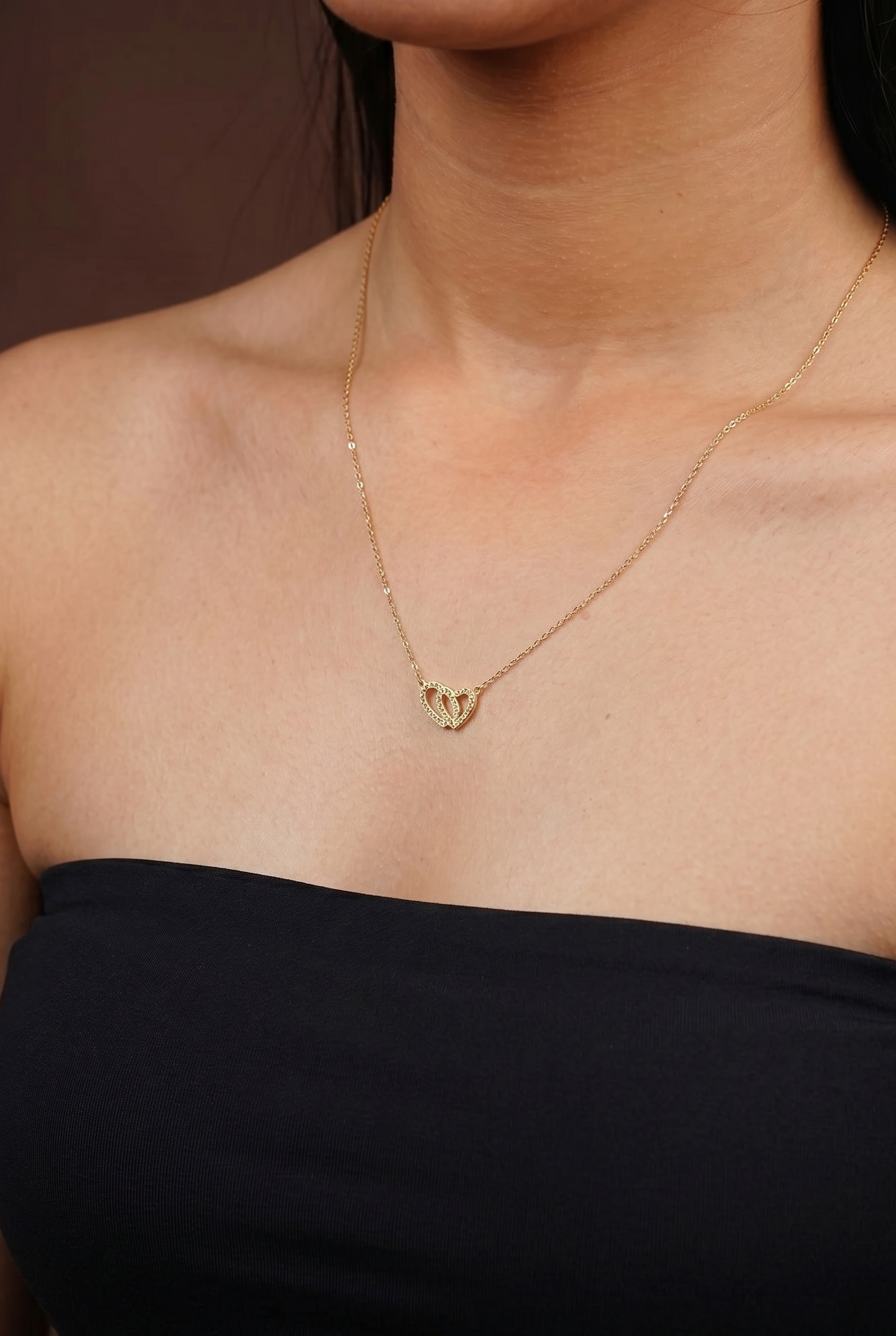 Gold necklace with a pendant worn by a person against a neutral background