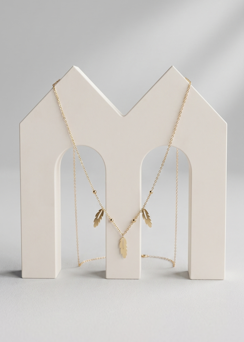 Necklace on a white jewelry stand against a light gray background