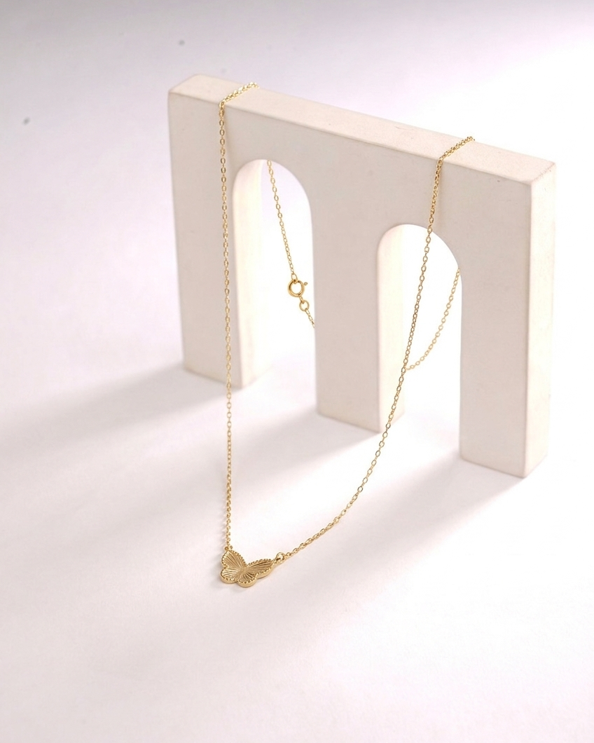 Gold necklace on a white stand with a plain background