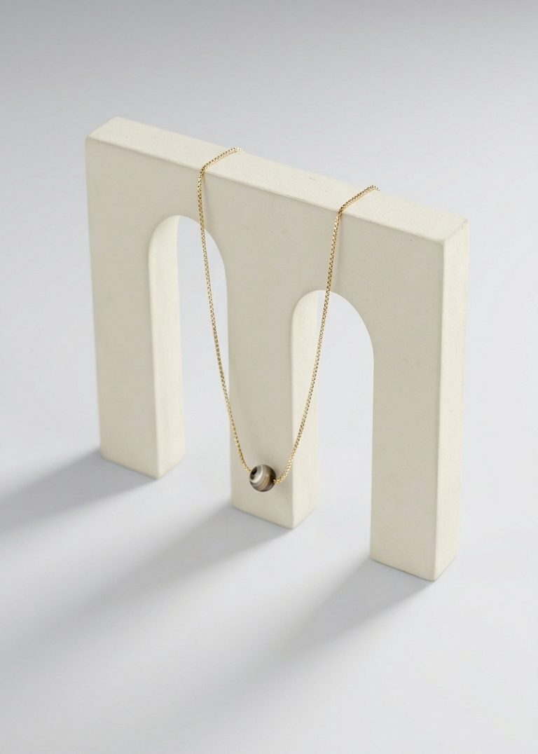 Necklace displayed on a white block with a neutral background