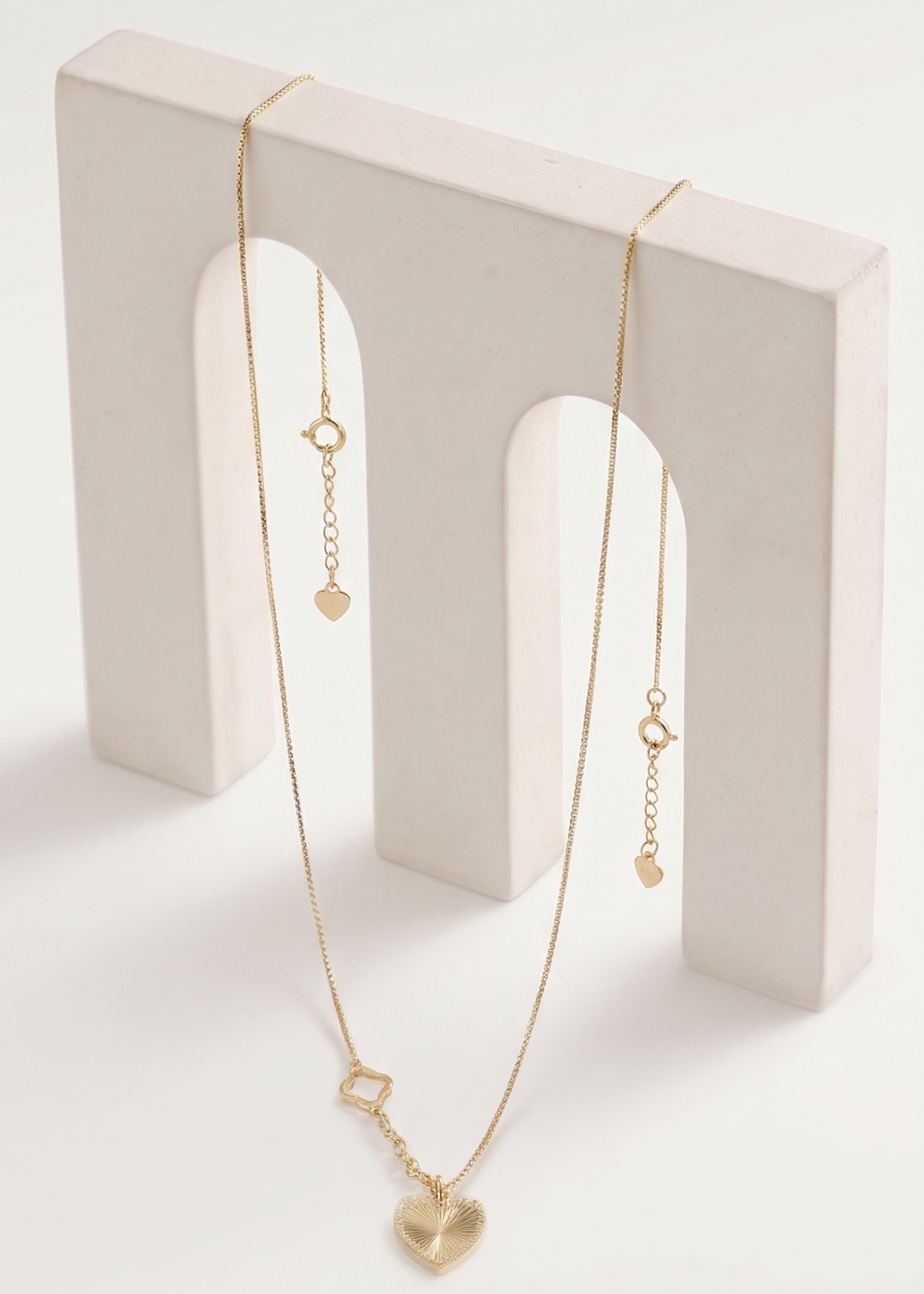 Gold necklace on a white stand with a white background
