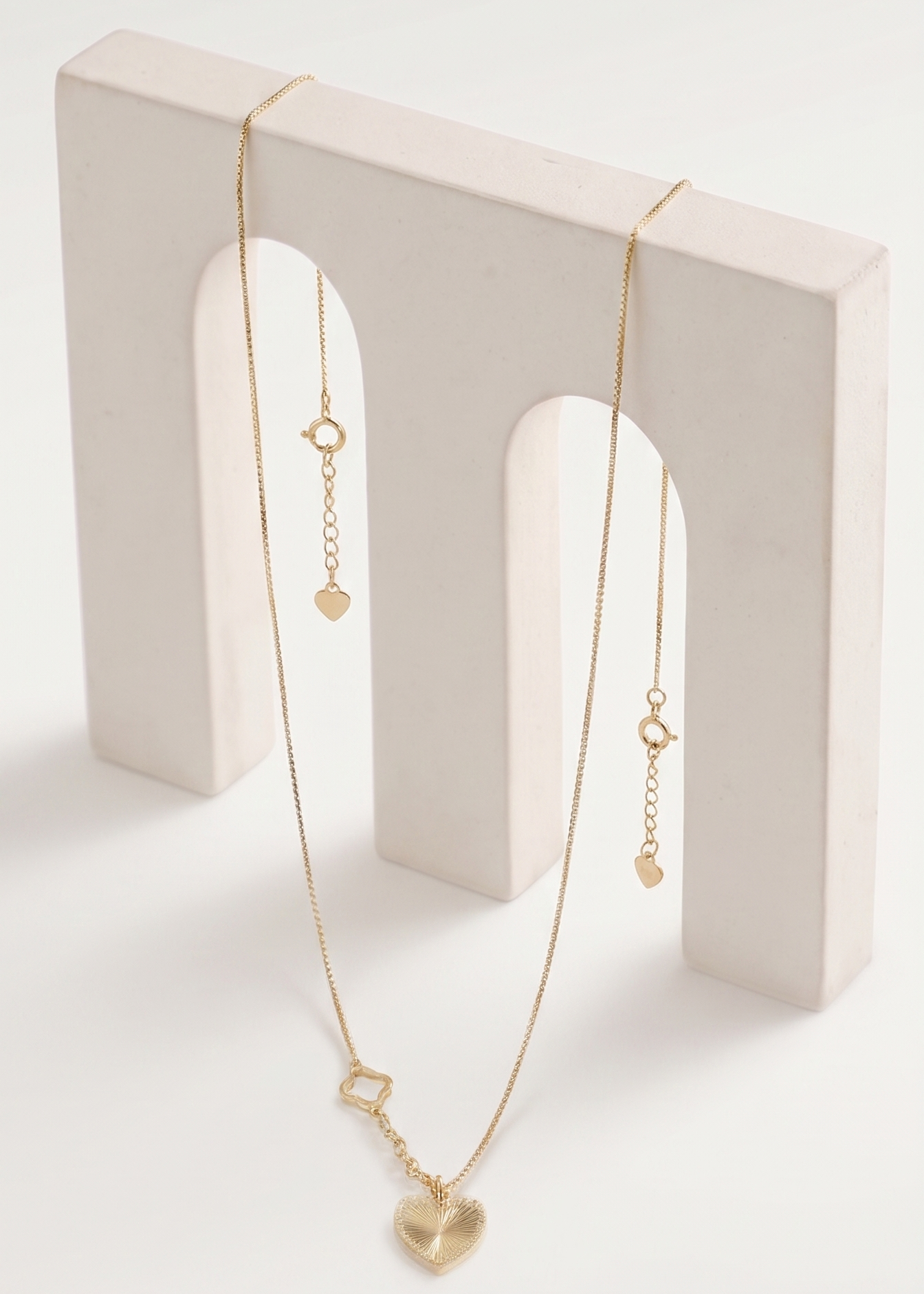 Gold necklace on a white stand with a white background